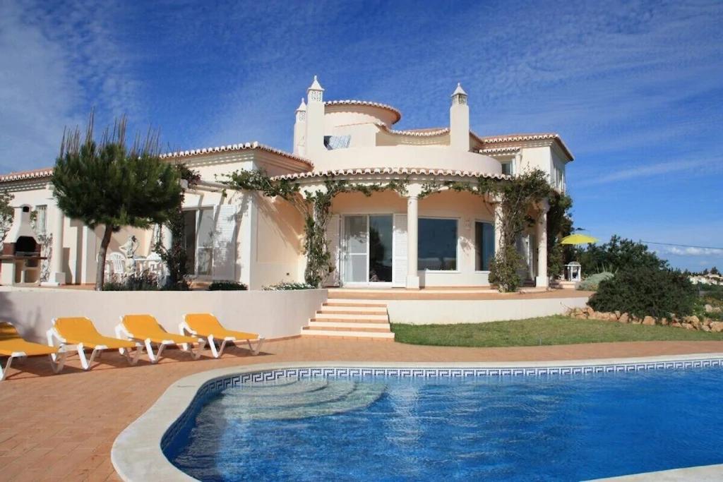 een huis met een zwembad ervoor bij Villa with beautiful see views & spacious garden in Ferragudo