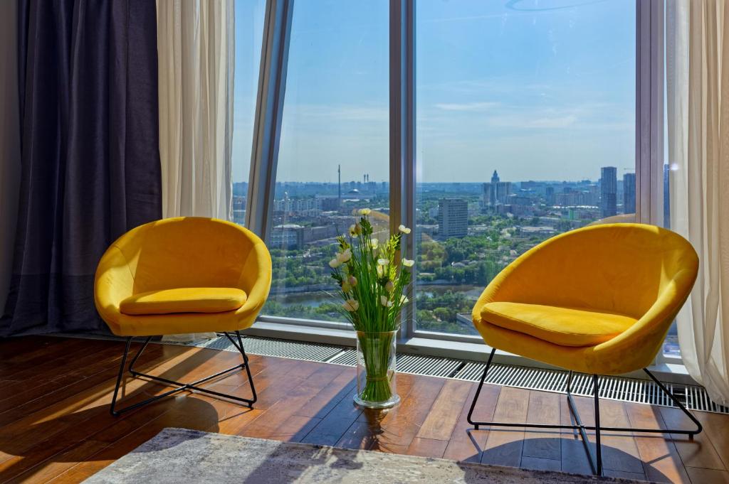 two yellow chairs and a vase of flowers in a window at SkyRrent24 Moscow City sunny apartment Москва Сити in Moscow