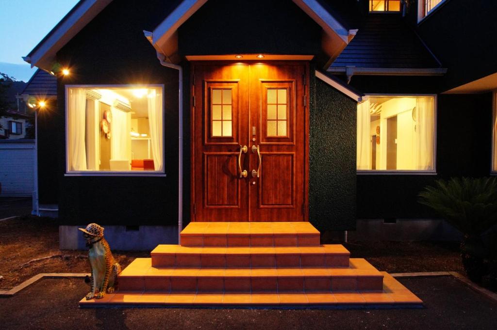 um gato sentado em frente a uma casa com uma porta de madeira em Famille Omuro - Vacation STAY 98191 em Ito