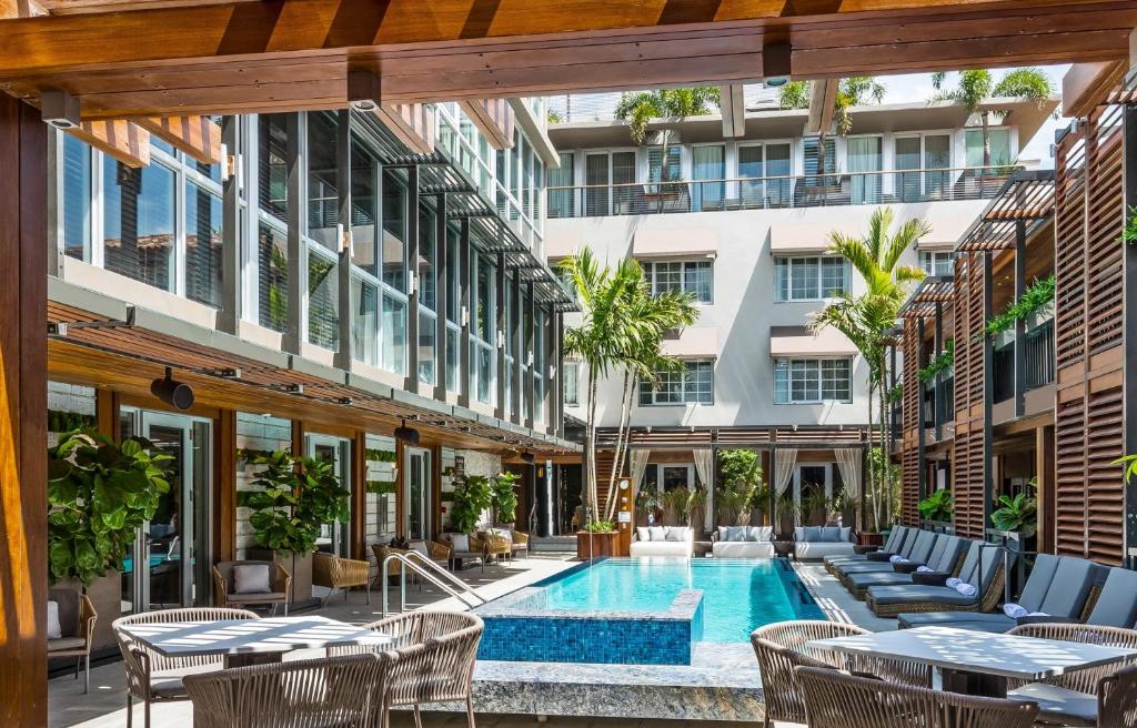 an outdoor patio with a swimming pool and tables and chairs at Lennox Miami Beach in Miami Beach