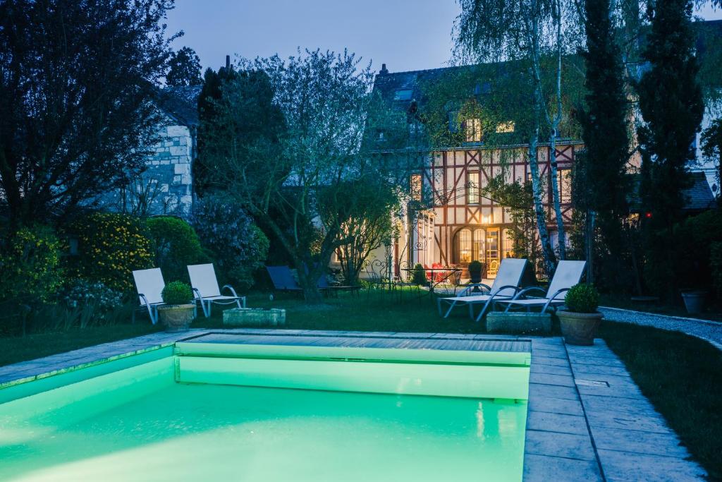 - une piscine dans une cour avec des chaises et une maison dans l'établissement Hotel Spa - Au Charme Rabelaisien, à Amboise