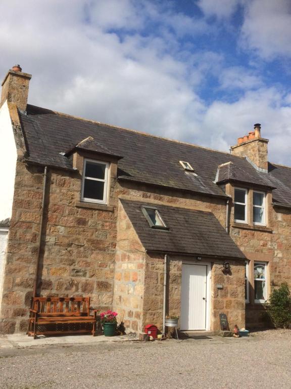 una vieja casa de ladrillo con una puerta blanca en Lettoch Farm en Dufftown