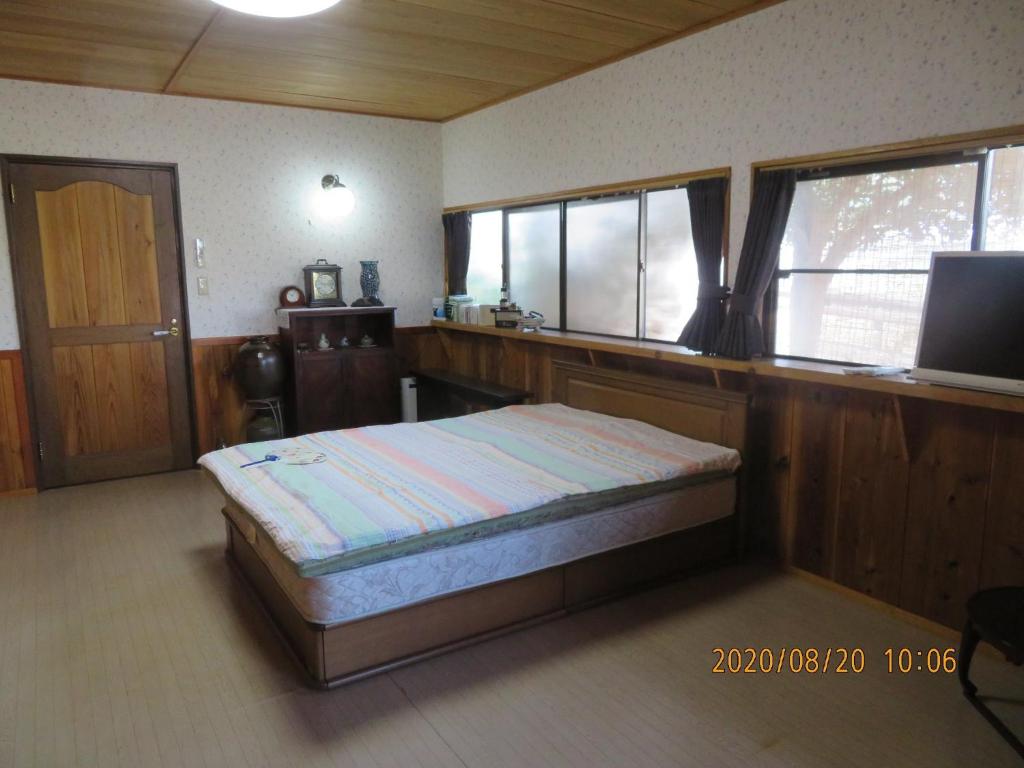 Guest House Miyazu Kaien - Vacation STAY 99191 في ميازو: غرفة نوم بسرير وتلفزيون ونوافذ