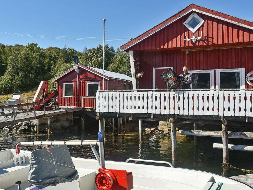 a woman standing on a dock next to a red building at 6 person holiday home in Oksvoll in Oksvoll
