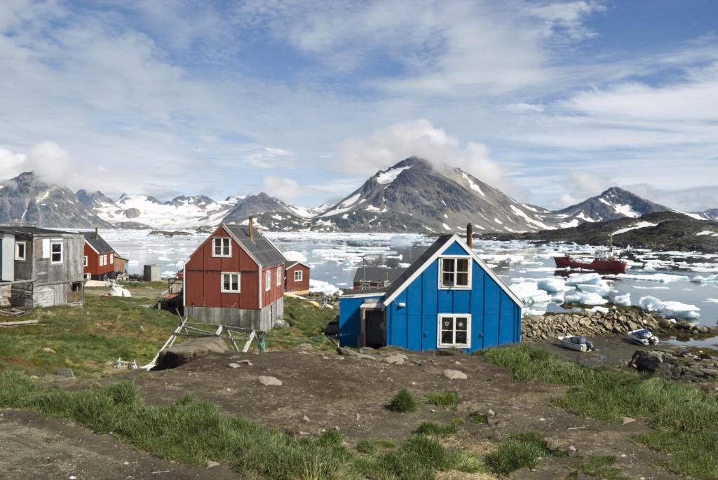 un groupe de maisons avec des montagnes en arrière-plan dans l'établissement Igdlo Guesthouse, à Narsaq