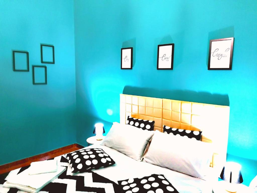 um quarto azul com uma cama com almofadas pretas e brancas em CasaCasetta Suite Appartamento Indipendente em Taranto