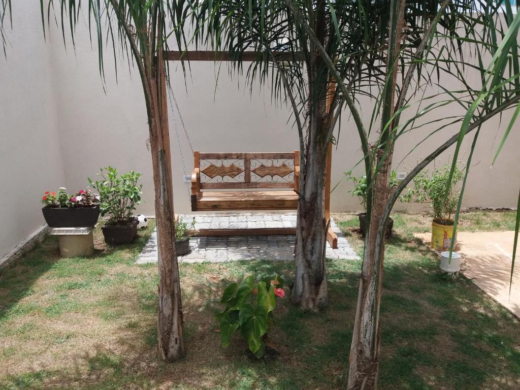 a wooden bench sitting between two trees in a yard at Casa em Capitolio in Capitólio