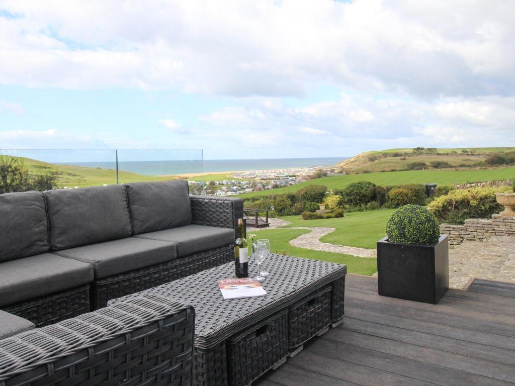 a patio with a couch and a table on a deck at Burton View in Burton Bradstock