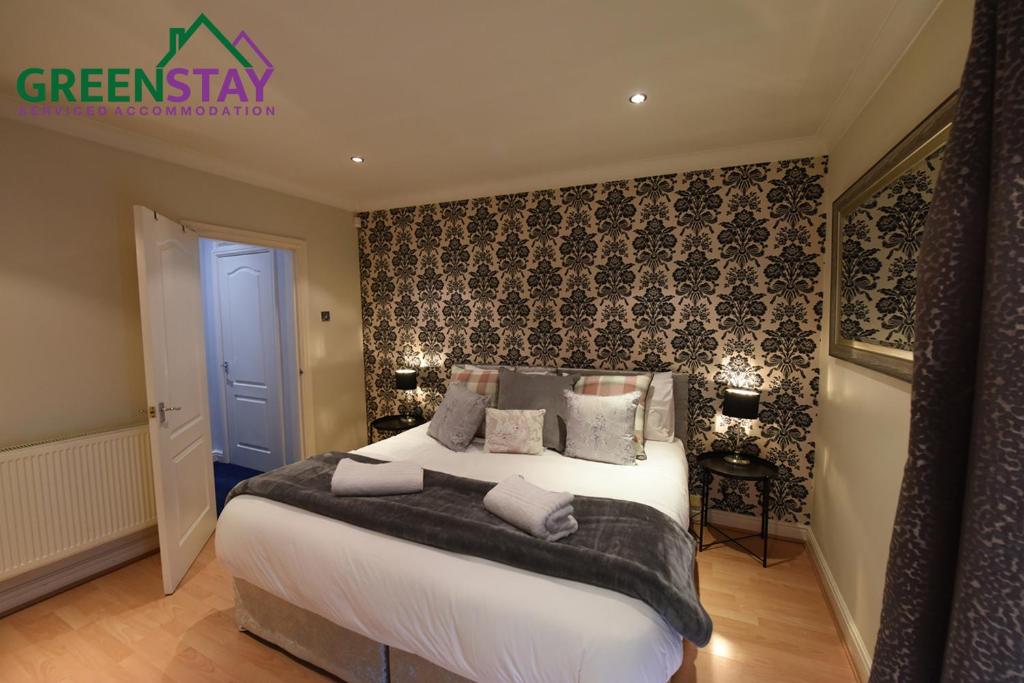 a bedroom with a large bed with black and white wallpaper at "Honeysuckle House Chester" by Greenstay Serviced Accommodation - Large 3 Bed House, Sleeps 6, Perfect For Contractors, Business Travellers, Families & Groups in Chester