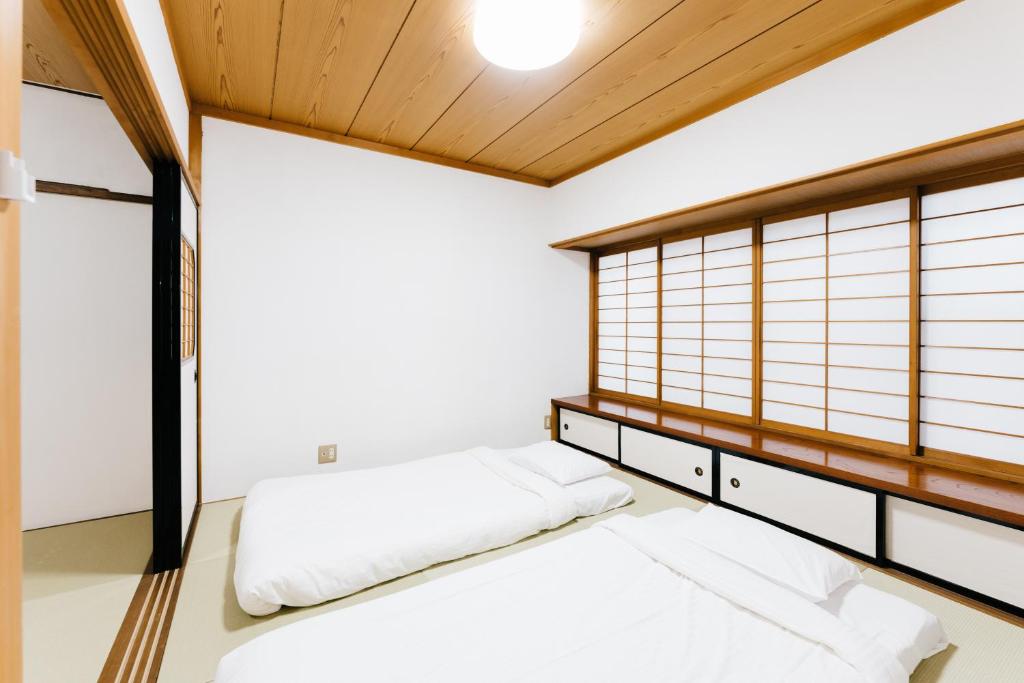 1 dormitorio con paredes blancas y ventana grande en B&B MIKAWA 3 - Kanazawa Fish Harbour, en Kanazawa