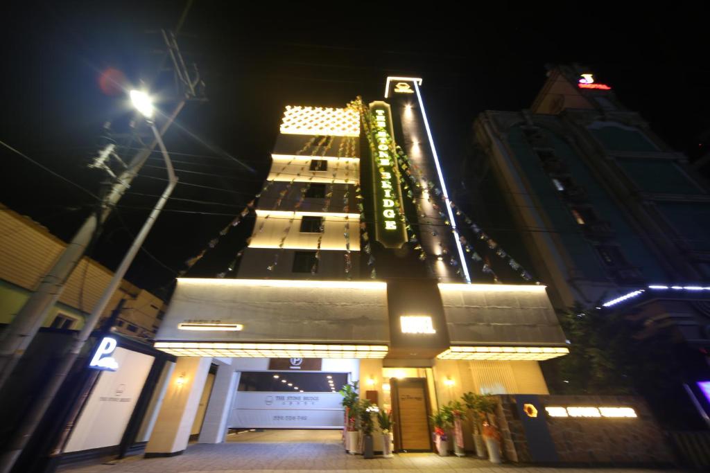 a tall building at night with a lit up building at The Stone Bridge Hotel Sasang in Busan