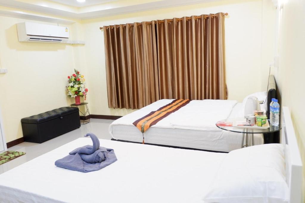 a bedroom with two beds and a table at ดอยตุง ฮันนาห์ โฮมสเตย์ in Ban Pa Kluai La Hu