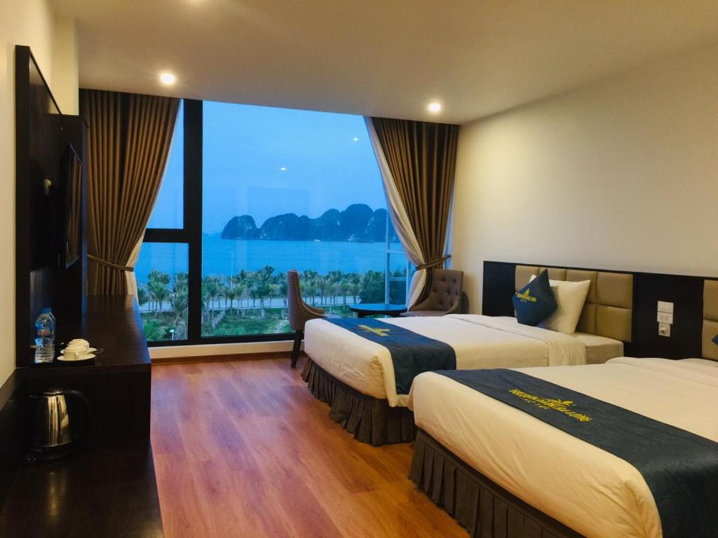 a hotel room with two beds and a large window at Golden Palm HaLong Hotel in Ha Long