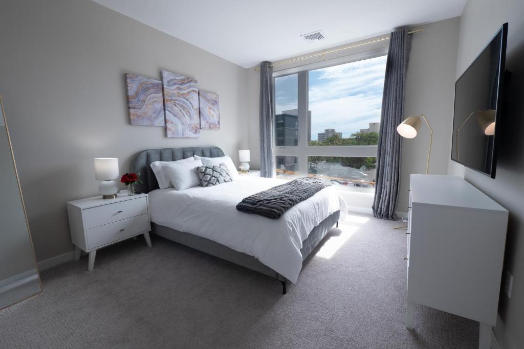 a bedroom with a bed and a large window at Luxury Furnished Apartments by Hyatus Downtown at Yale in New Haven