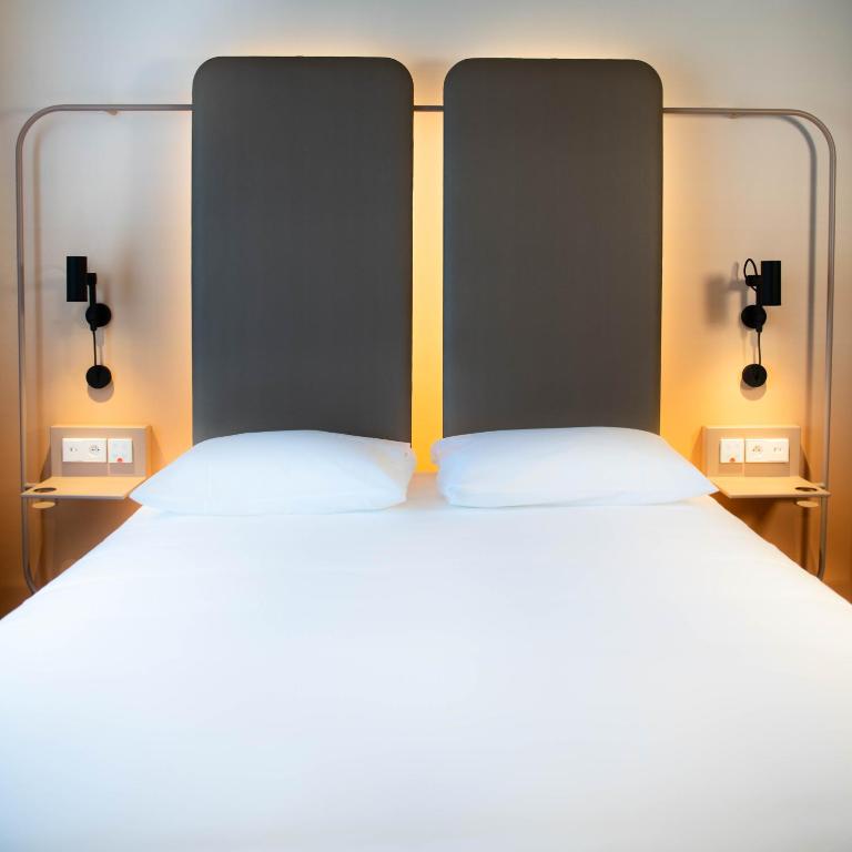 a large bed with two white pillows and two lights at YOU Are Deauville in Deauville