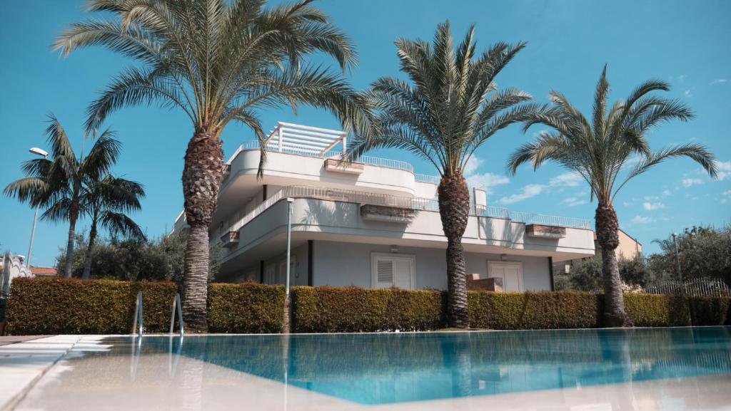 a house with palm trees in front of a swimming pool at Villa Galati Resort in Mascali