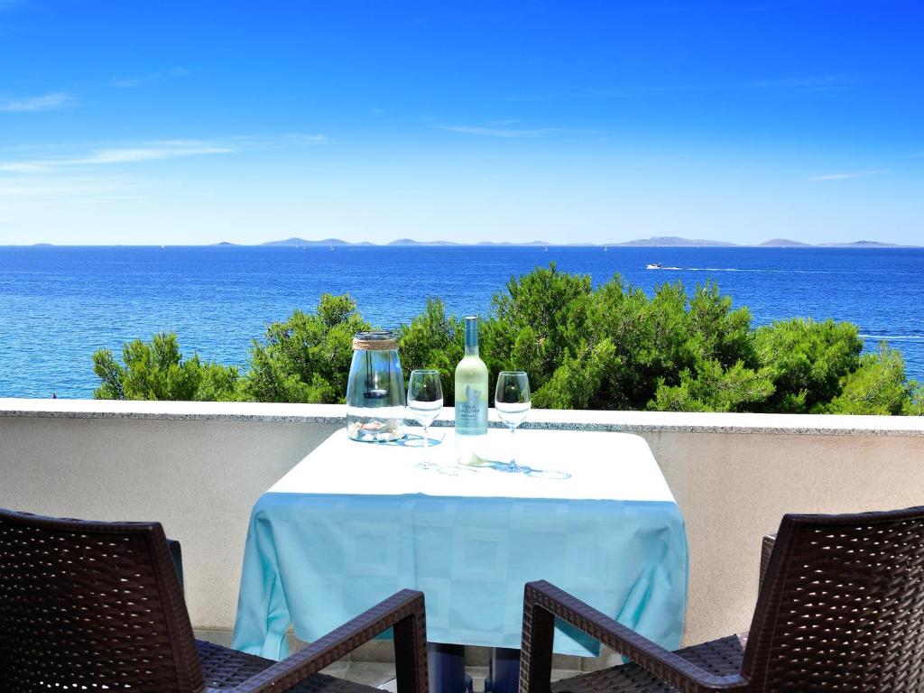 a table with wine bottles and glasses on a balcony at Villa Ana in Murter