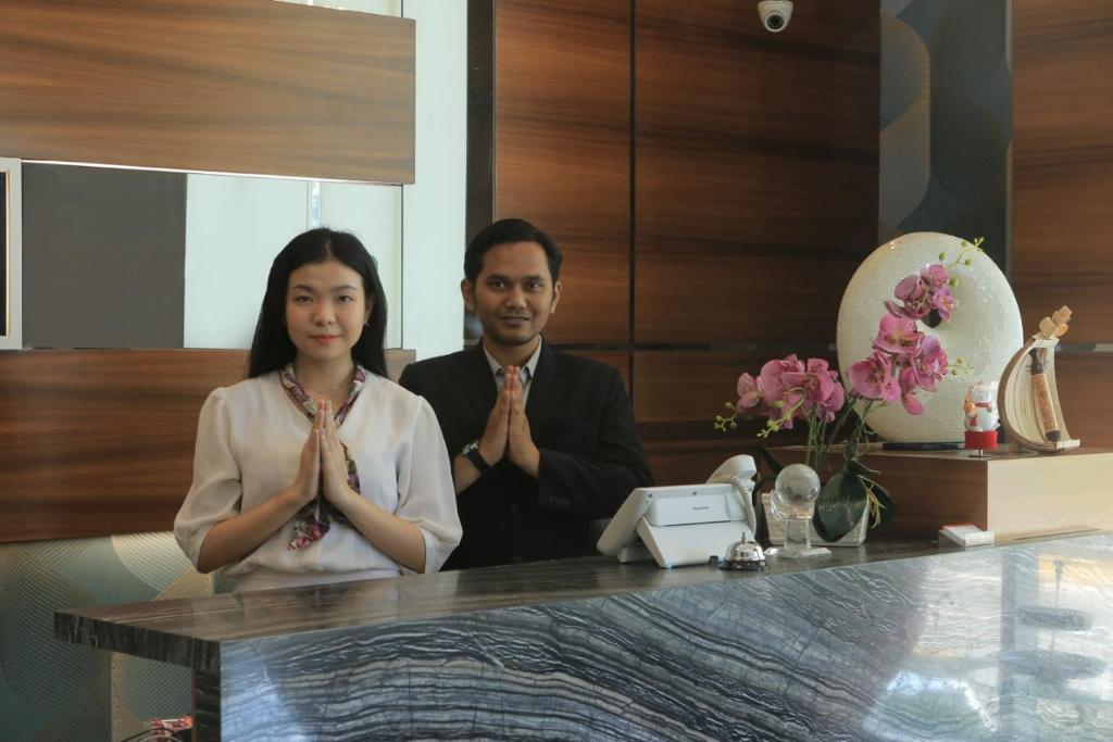 a man and a woman sitting at a table praying at Smarthomm Ancol Jakarta in Jakarta
