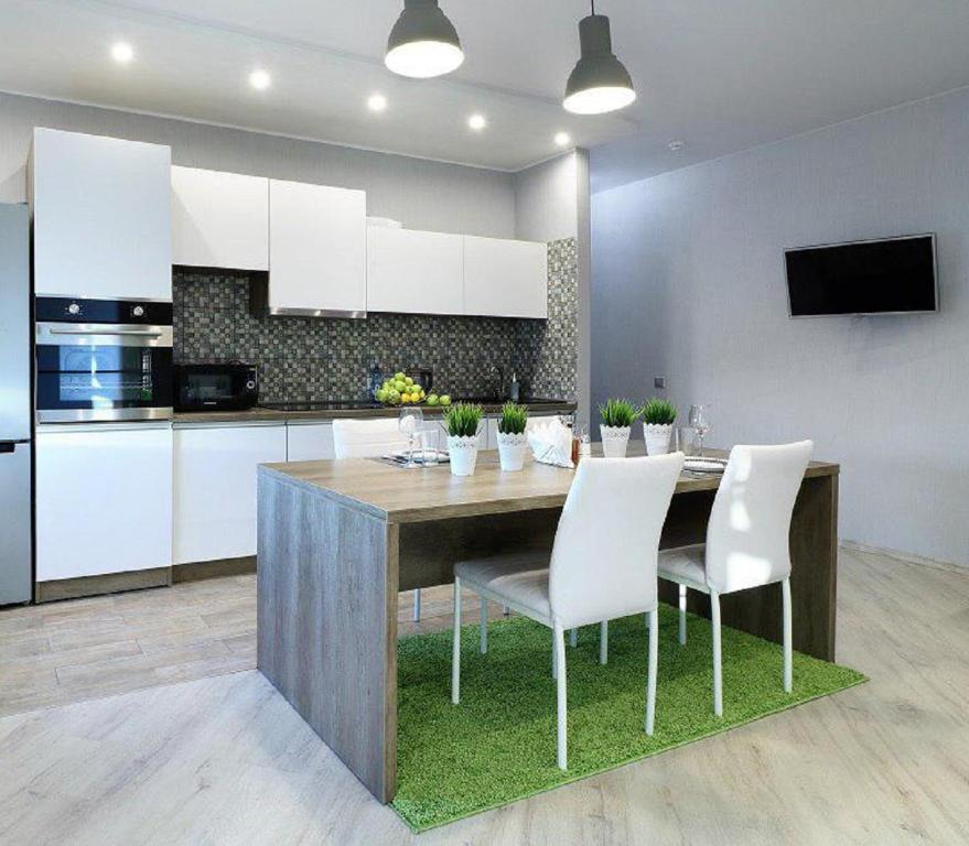 a kitchen with a wooden table and white chairs at PaulMarie Apartments on Yakubovskogo in Mogilev