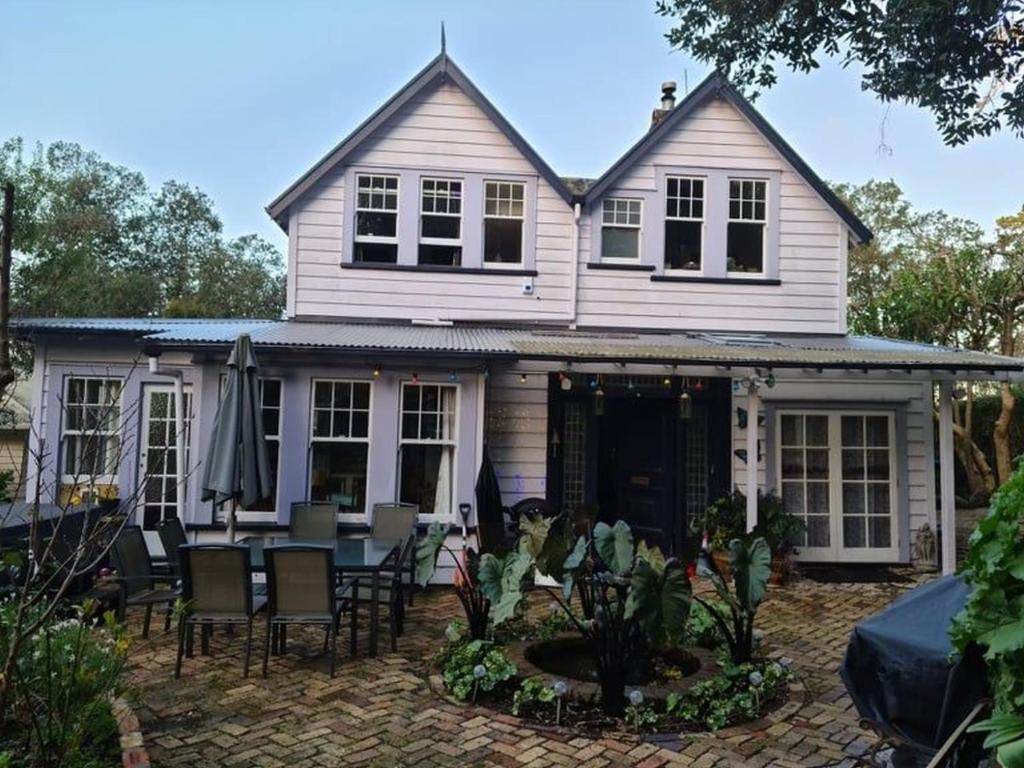 Cette maison blanche dispose d'une terrasse, d'une table et de chaises. dans l'établissement Dovecote House, à Auckland