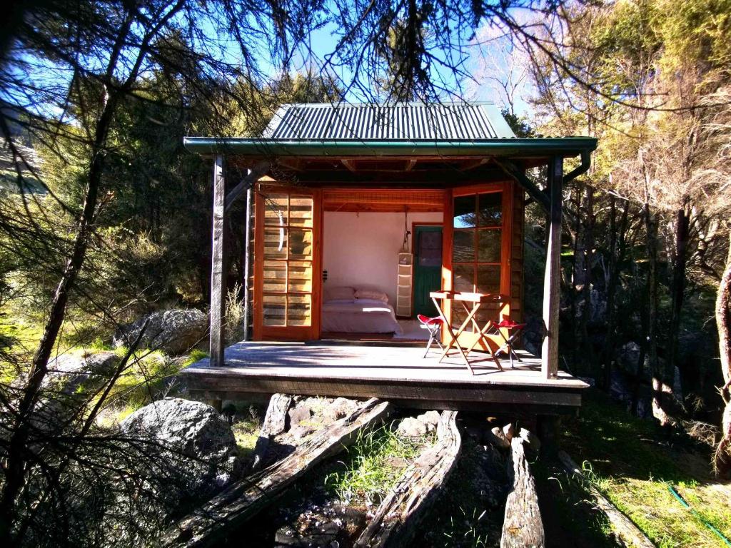 a small cabin on a wooden platform in the woods at Manaaki Mai, Rustic Retreat Bush Cabin in Christchurch
