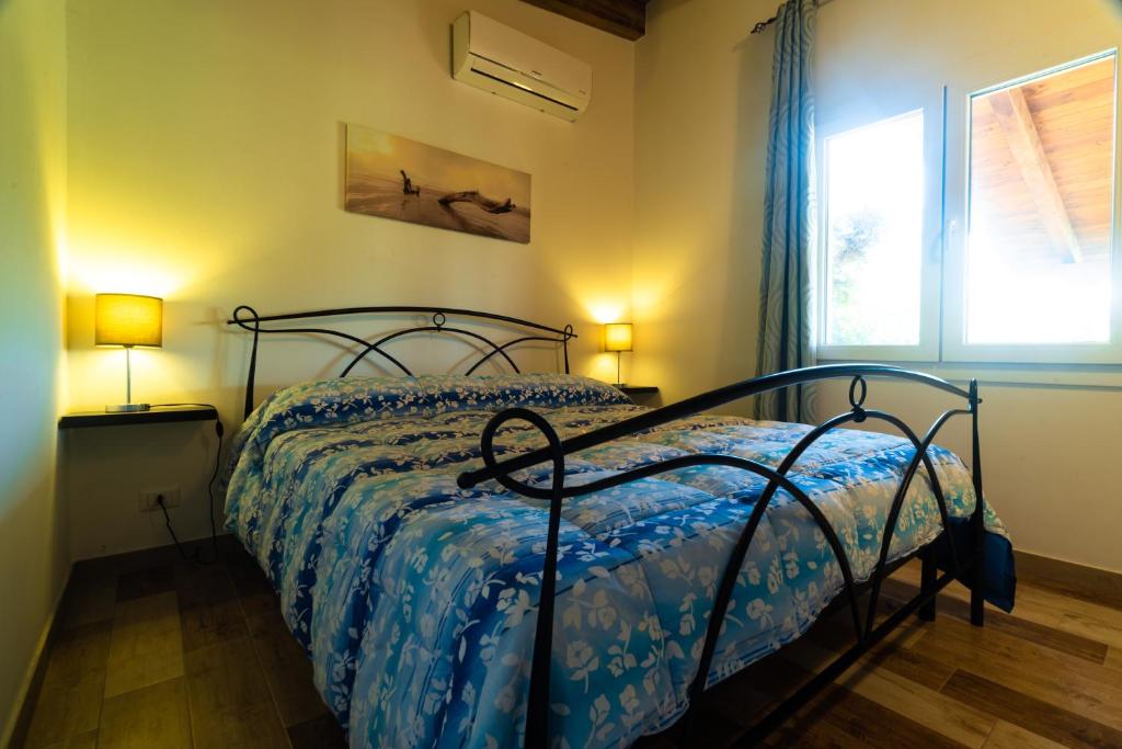 een slaapkamer met een bed met een blauw dekbed en een raam bij Bonsai B&B Alghero in Santa Maria la Palma