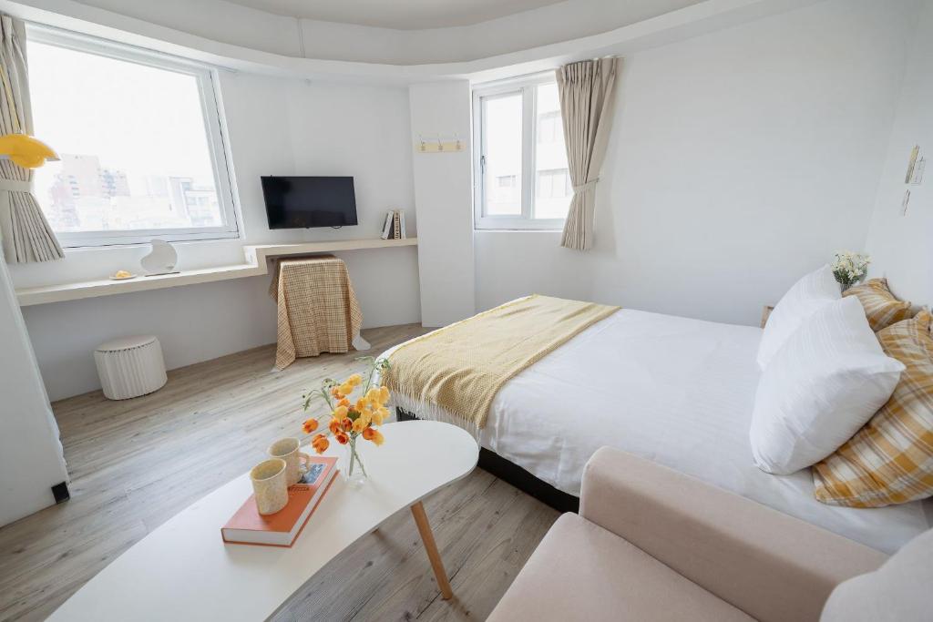 a white bedroom with a bed and a couch at June in Tainan