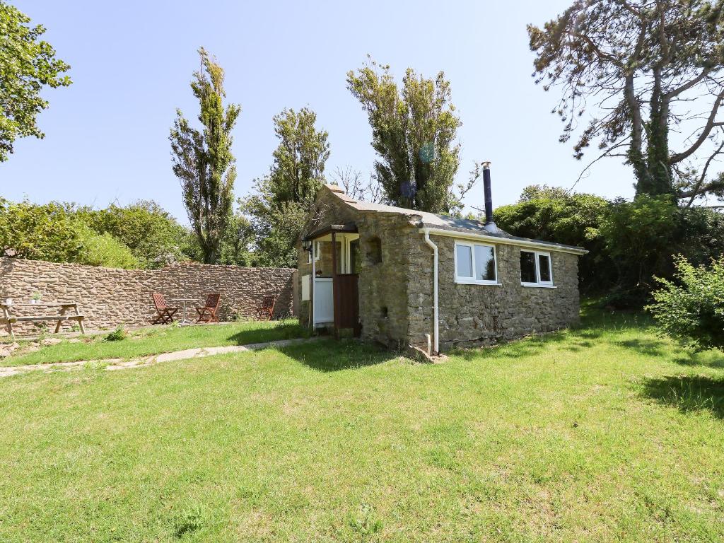 ein altes Cottage aus Stein mit einem Rasenhof in der Unterkunft Washingpools in Swyre
