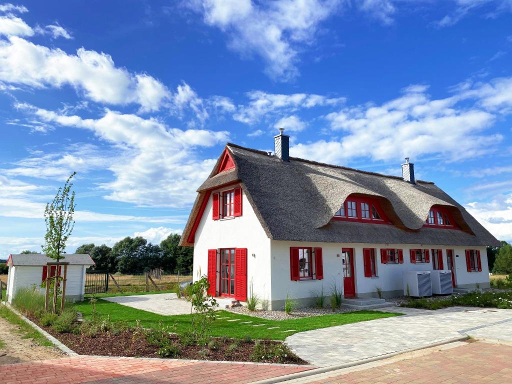 a white and red house with red shutters at Haus zwischen Mühle und Meer in Boiensdorf