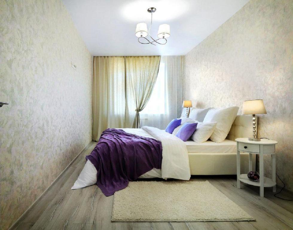 a bedroom with a bed with purple sheets and a window at PaulMarie Apartments on Chigrinova in Mogilev