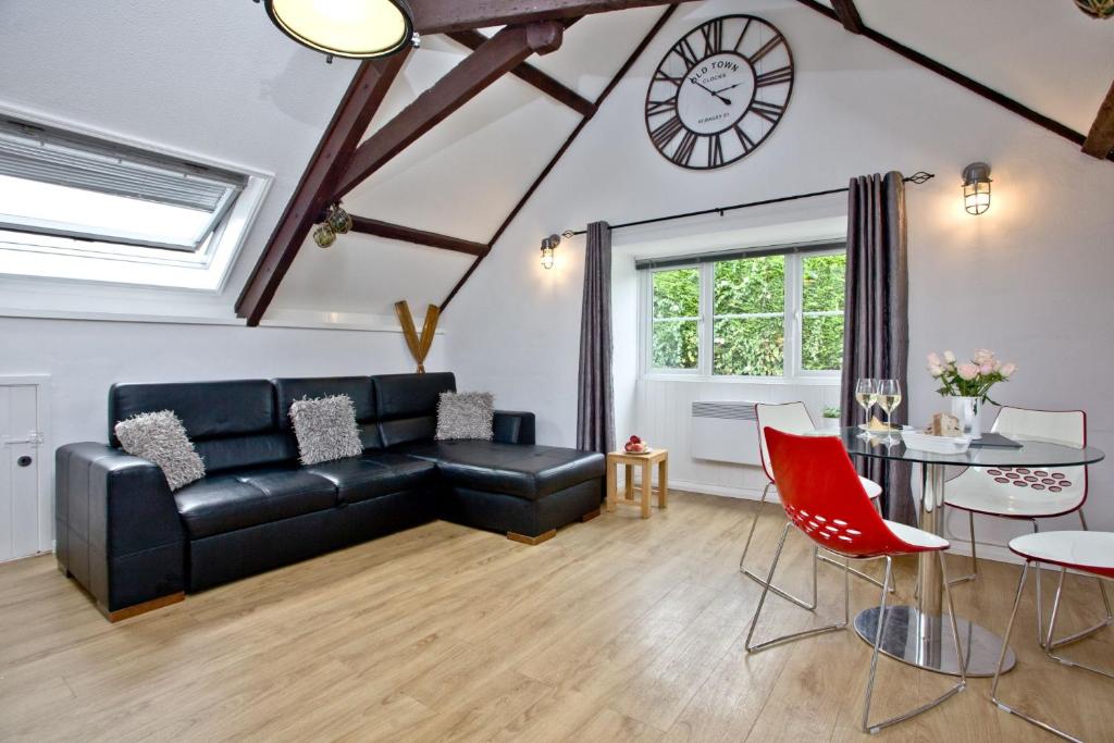 a living room with a black couch and a clock on the wall at Anchor Cottage, Strete, Dartmouth in Strete
