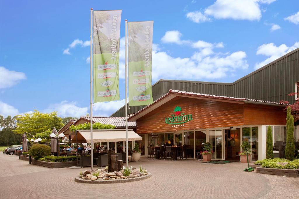 een restaurant met vlaggen voor een gebouw bij Aparthotel Delden in Delden