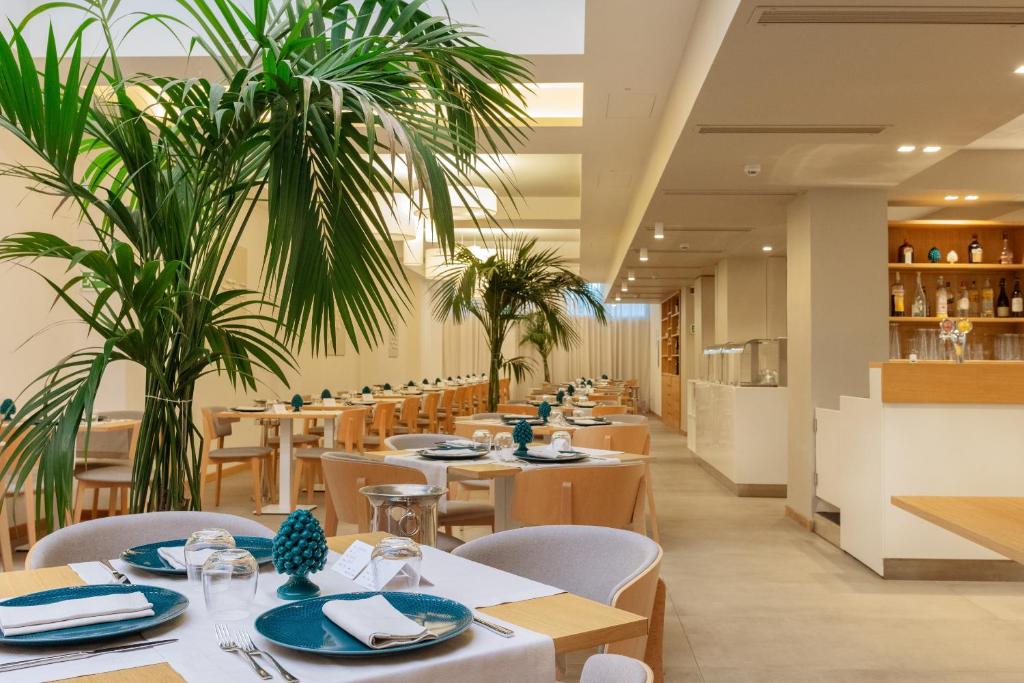 a restaurant with tables and chairs and palm trees at Albatros Beach Hotel in Letojanni
