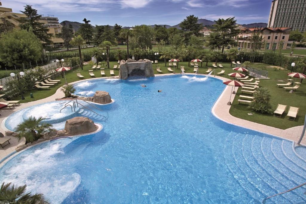 a large swimming pool in a resort with umbrellas at Hotel Terme All'Alba in Abano Terme