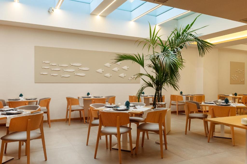 a dining room with tables and chairs and a plant at Albatros Beach Hotel in Letojanni