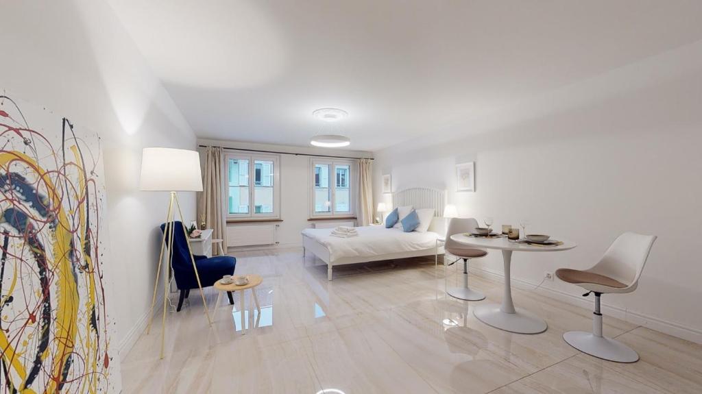 Habitación blanca con cama, mesa y sillas en DA-DA Gallery Appart - modern and luxury studio in Boudry, en Boudry