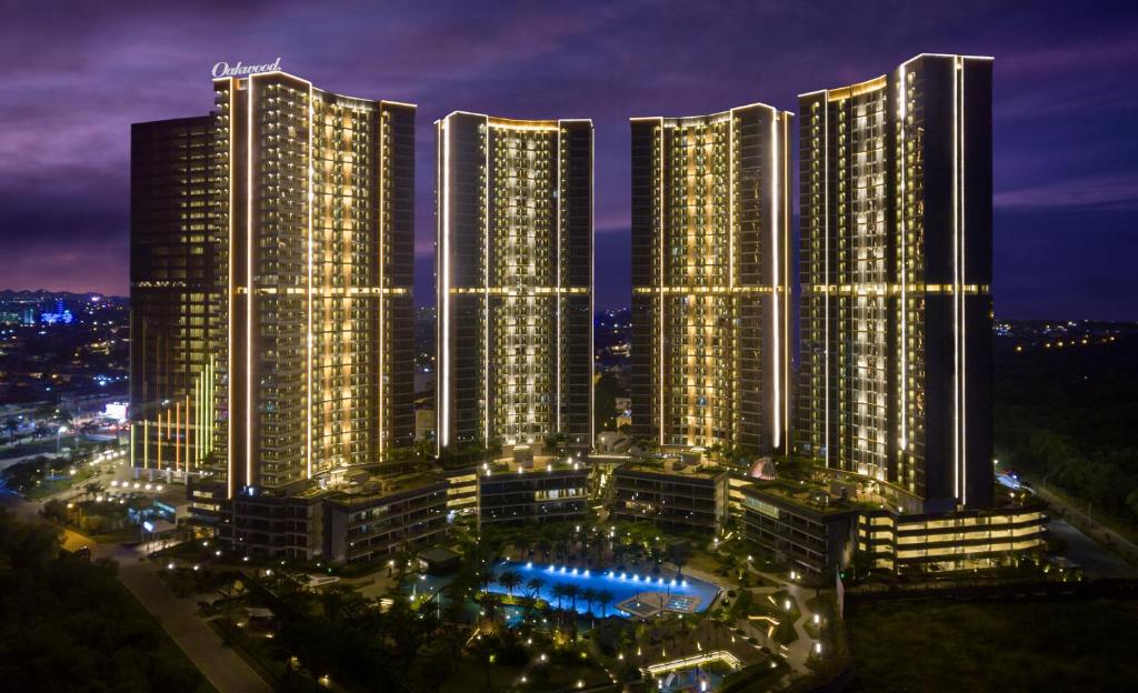 a group of tall buildings in a city at night at Oakwood Apartments PIK Jakarta in Jakarta