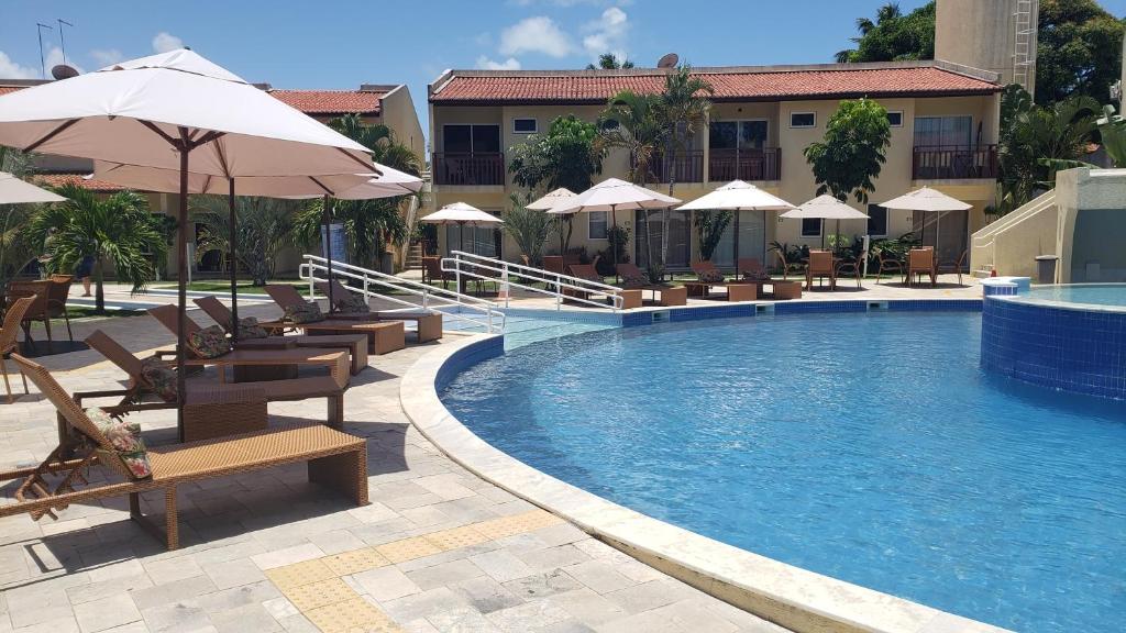 una piscina con sedie e ombrelloni accanto a un hotel di Solar Água Apart Pipa a Pipa