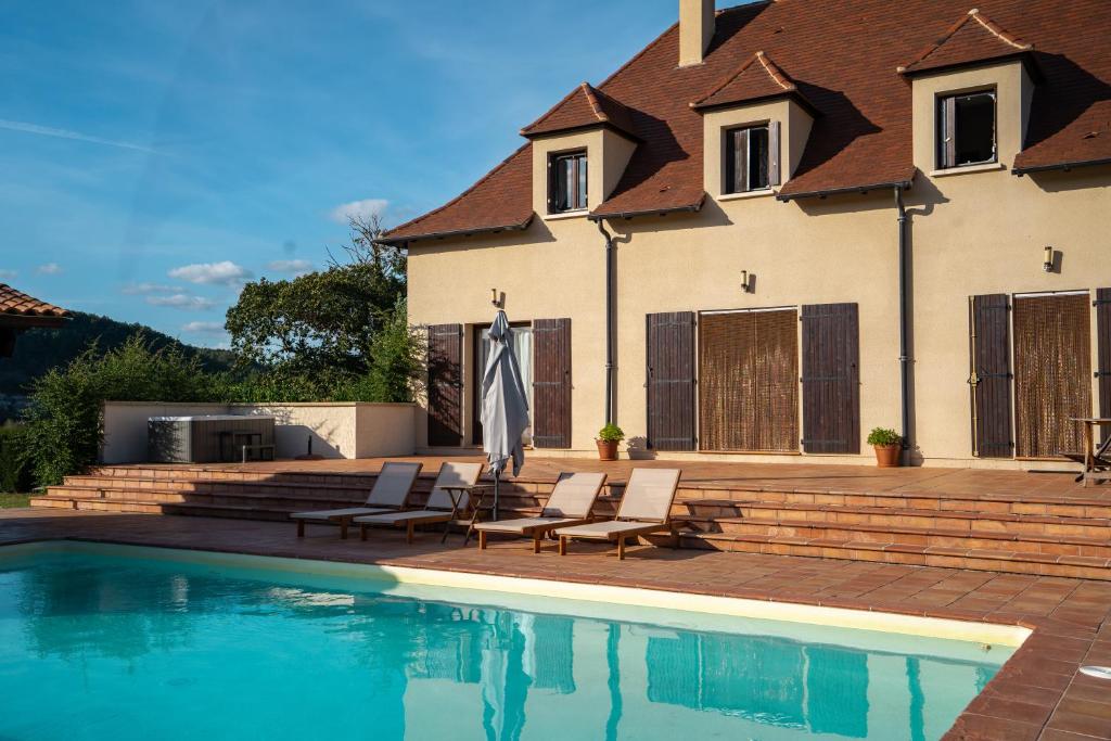 ein Haus mit einem Pool, 2 Stühlen und einem Sonnenschirm in der Unterkunft Maison de Vacances - Domaine de la Couvée in Calès