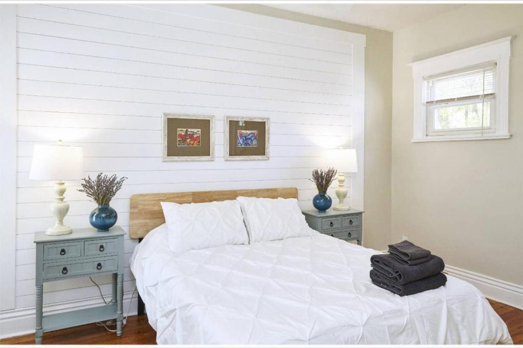 a white bedroom with a bed with two night stands at Heart of Highlands 3BR Loft in Louisville