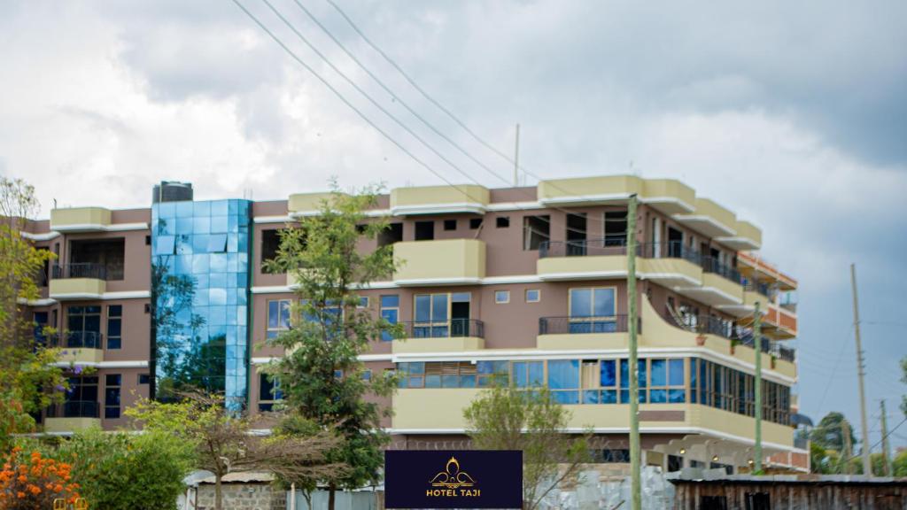 un immeuble d'appartements avec un panneau en face de celui-ci dans l'établissement HOTEL TAJI, à Nanyuki