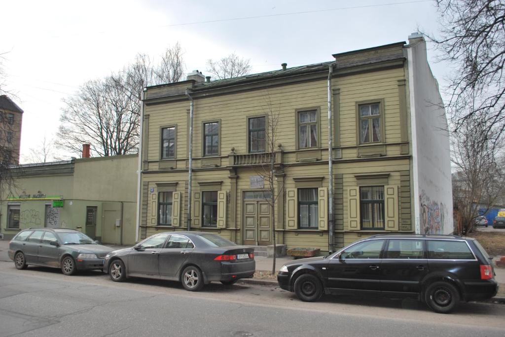 two cars parked in front of a yellow building at Muzeja apartamenti in Rīga