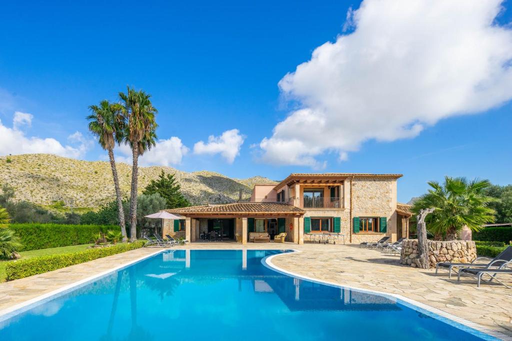 una casa con piscina frente a una casa en Villa Les Oliveres Antonia By SunVillas Mallorca, en Port de Pollença (Puerto Pollensa)