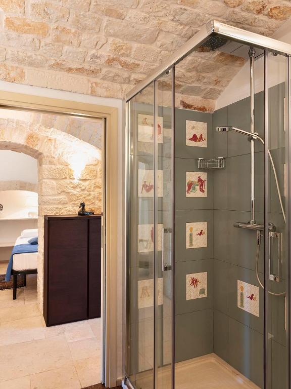 W łazience znajduje się prysznic ze szklanymi drzwiami. w obiekcie Trulli Uliveto Acquafonda w Alberobello