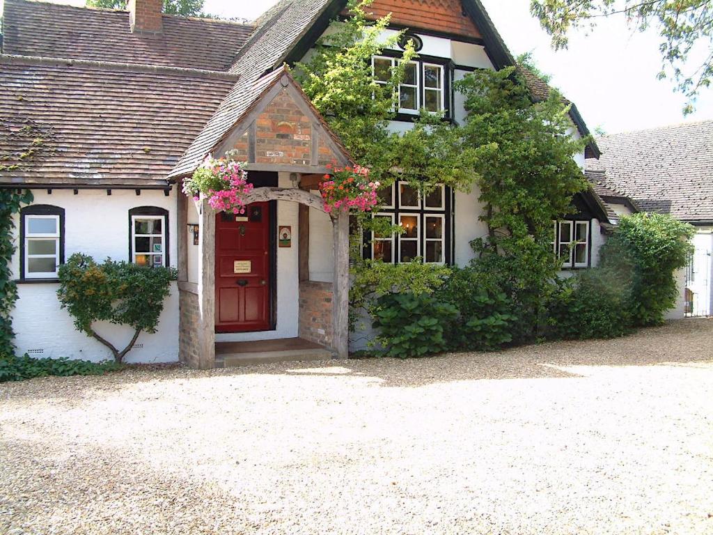 een huis met een rode deur met bloemen erop bij West Lodge Hotel in Aylesbury