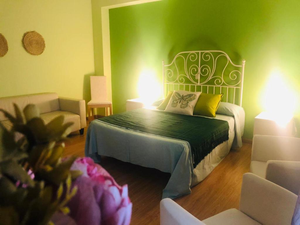 zieloną sypialnię z łóżkiem i 2 krzesłami w obiekcie Hospedería de Juan w mieście Fuentidueña de Tajo