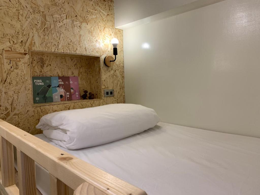 a bed with a white pillow on top of it at 墾丁秋莊會館 附限量停車位 不保證有位置 無法事先預留 背包房無車位 預訂後記得加Line聯繫 in Hengchun