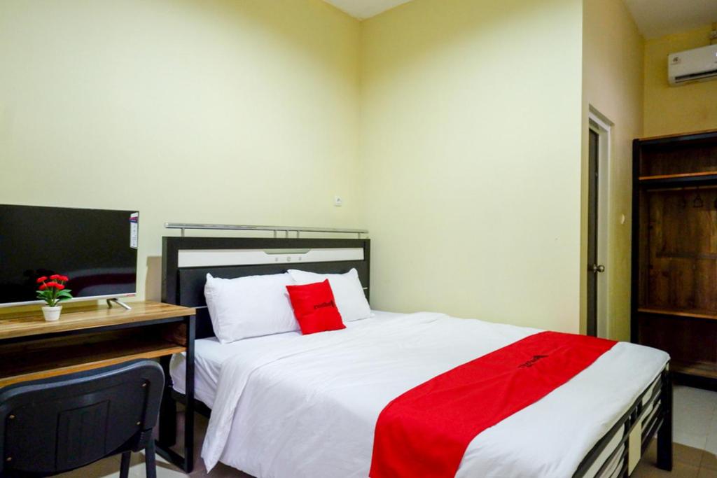a bedroom with a bed with a red blanket on it at RedDoorz @ Jalan Bali Cilacap in Gumilir
