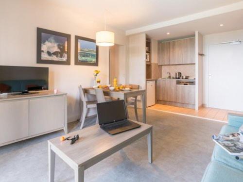 un salon avec une table avec un ordinateur portable dessus dans l'établissement Appartement plage de Trestraou 45m2, à Perros-Guirec