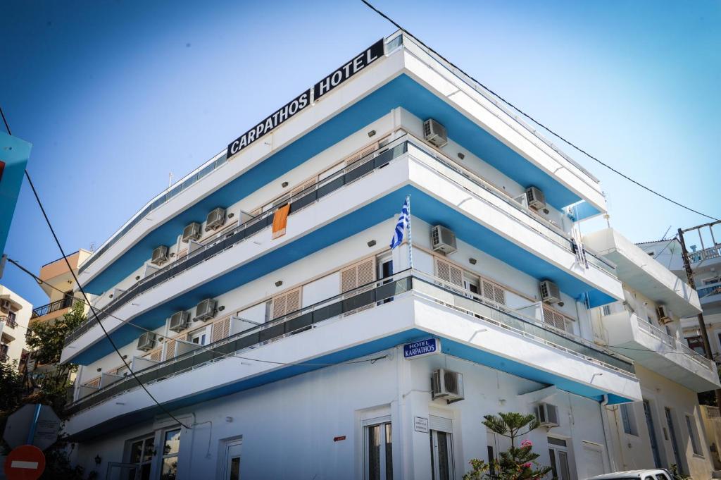 un grand bâtiment blanc avec des finitions bleues dans l'établissement Hotel Karpathos, à Karpathos